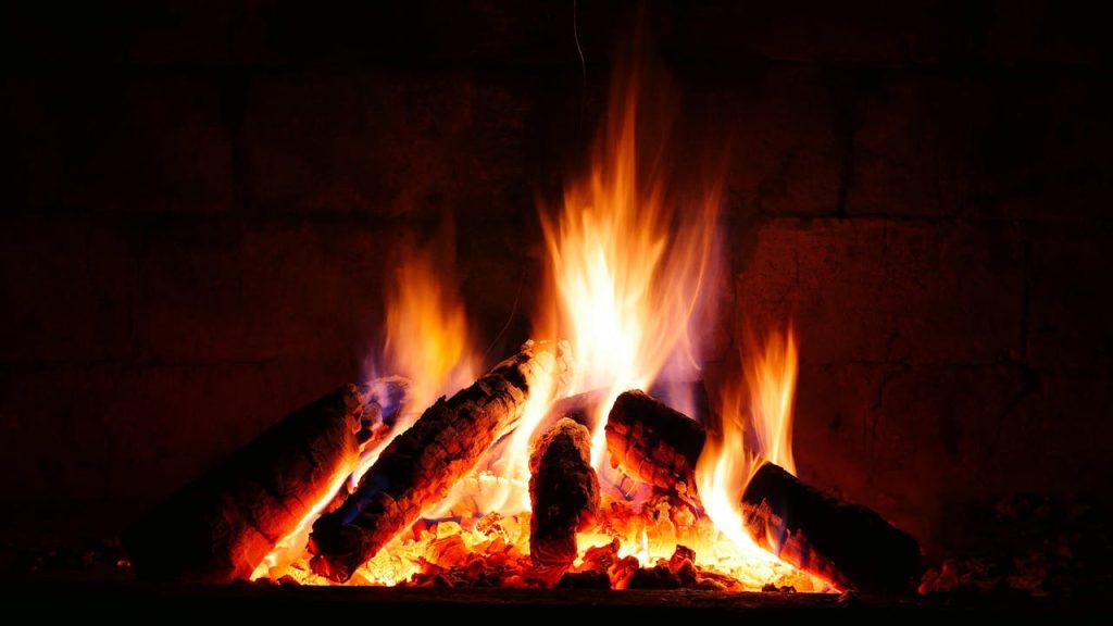 A close-up view of a crackling fire with glowing logs in a cozy fireplace.